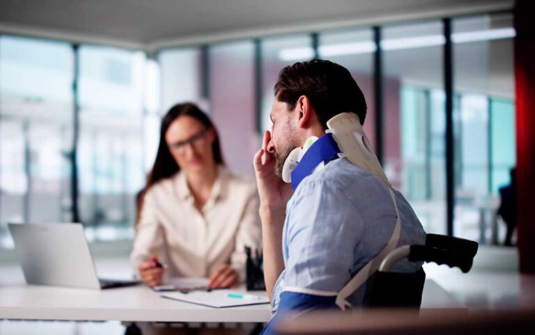 Two people sitting at a table reviewing documents after an accident, with medical paperwork and a laptop visible.