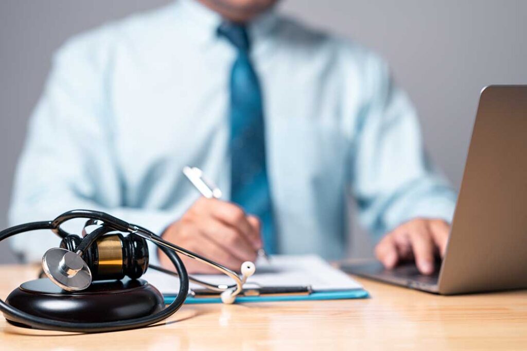 Injured person reviewing medical bills, pay records, and accident documents at a kitchen table.